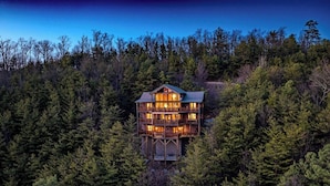A multi-story wooden cabin surrounded by dense forest.
