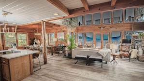 A spacious, open-plan living area with a wooden ceiling, large windows, and a cozy seating area.
