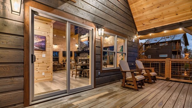Eine Holzhütte mit einer Terrasse, Schiebetüren und Sitzgelegenheiten im Freien.