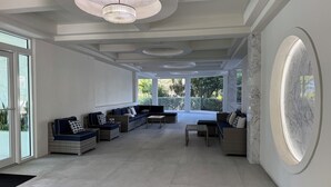 A spacious living area with a large sofa set, a coffee table, and a chandelier. - Top-Floor Partial Gulf View!  Steps from the Beach!  Little Tropical Paradise! (Marco Island)