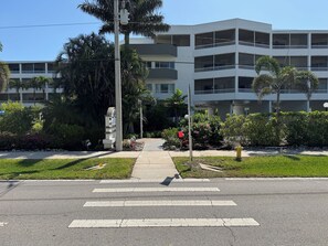 Un immeuble à plusieurs étages doté de balcons, d’un trottoir et d’un passage piéton.