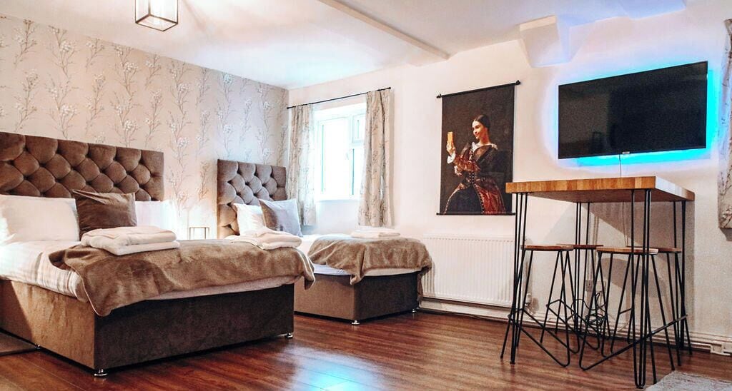 A bedroom with two beds, a TV, and a table.