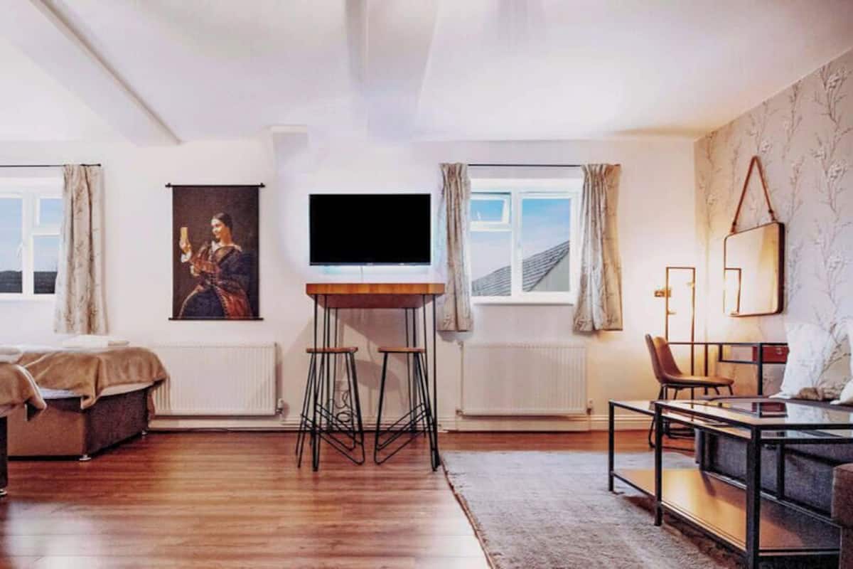 A modern bedroom with a bed, a TV, a desk, and a chair.