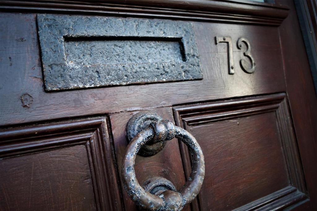 A door with a metal mail slot and a number '73' above it.