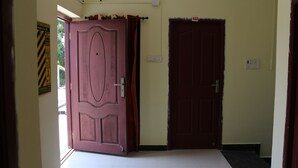 A hallway with two doors, one open and one closed, leading to rooms. - SaiRenu Residency  (Coimbatore)