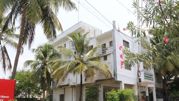A two-story building with a balcony on the second floor, surrounded by greenery and palm trees. - SaiRenu Residency  (Coimbatore)