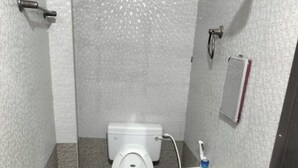 A small, compact bathroom with a toilet, sink, and a bucket on the floor. - SaiRenu Residency  (Coimbatore)