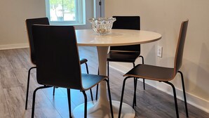 A dining area with a round table, four chairs, and a decorative glass bowl. - Modern apartment overlooking historic downtown Elloree, SC. (Elloree)