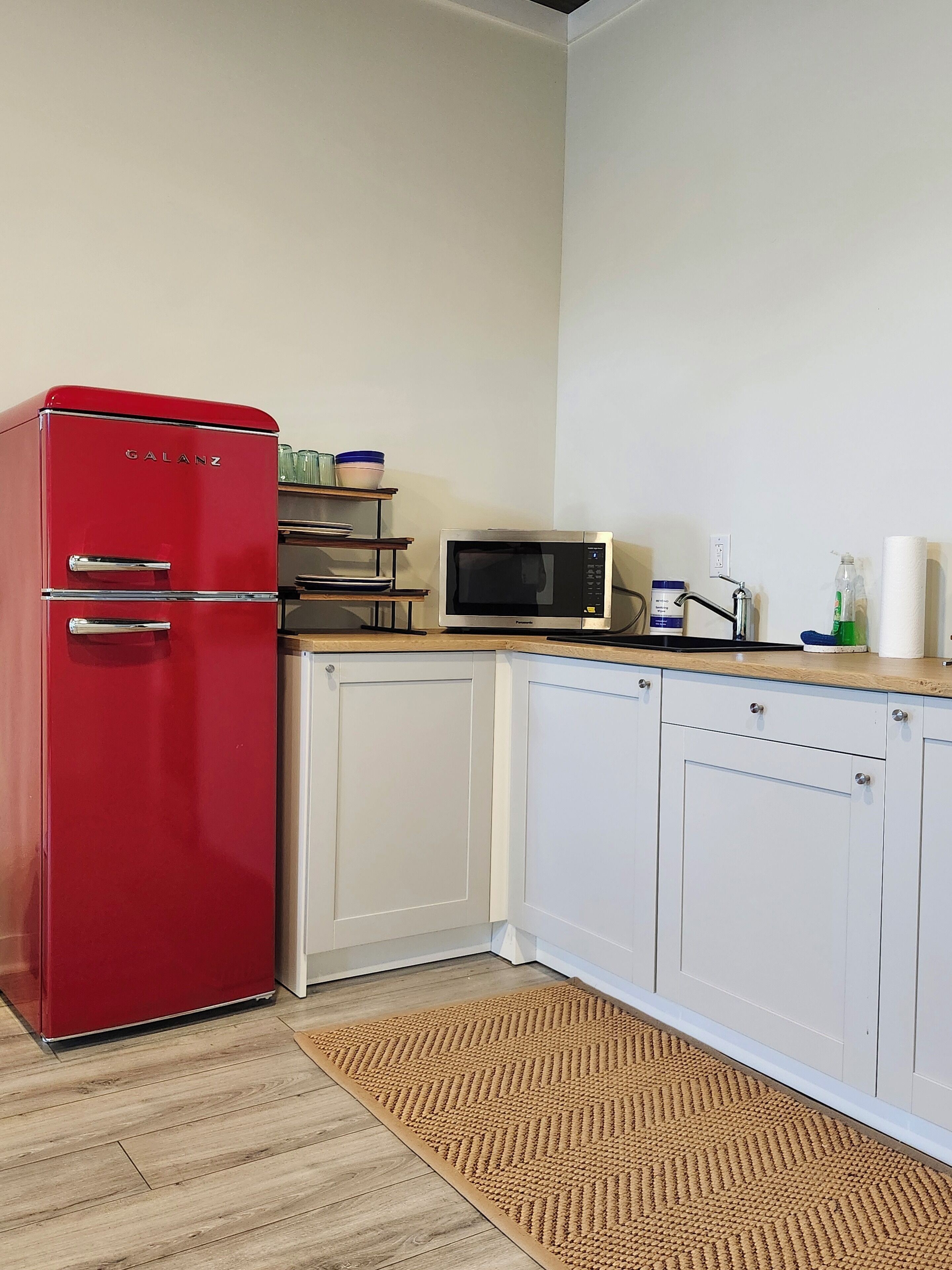 Una cocina compacta con un refrigerador rojo Galanz, un microondas y un lavamanos pequeño.