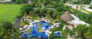 Un resort con varias piscinas, palmeras y zonas de descanso.