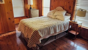 A wooden cabin bedroom with a bed, bedside lamps, and a dresser. - Cabin in the Woods (Franklin)