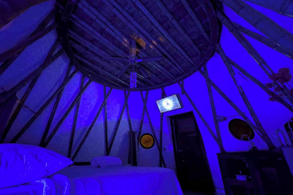 Ein Zimmer mit einem Bett, einem Fernseher und einer runden Deckenkonstruktion.