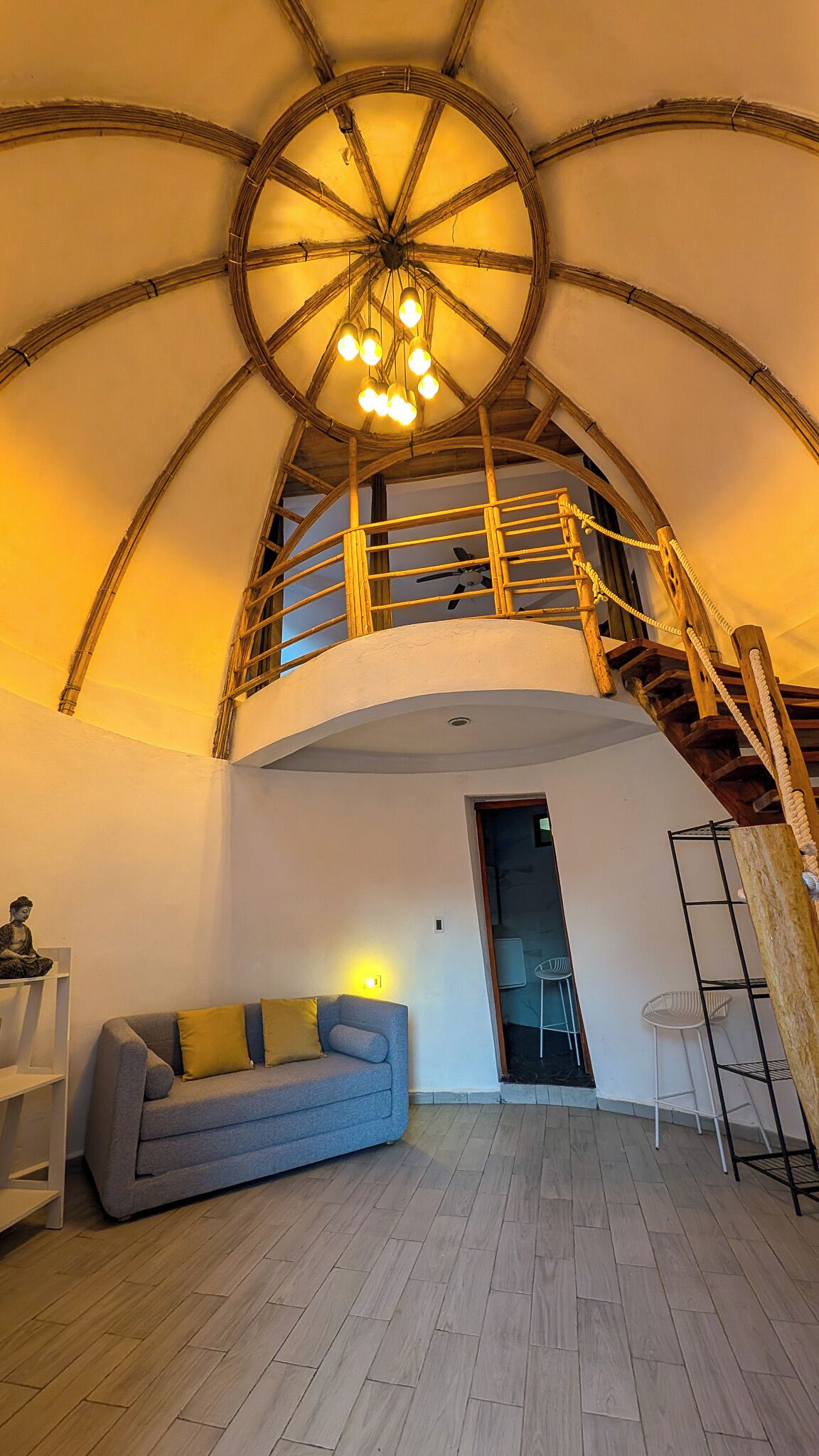 Un loft espacioso con techo alto, escalera de madera, sofá y un pequeño comedor.