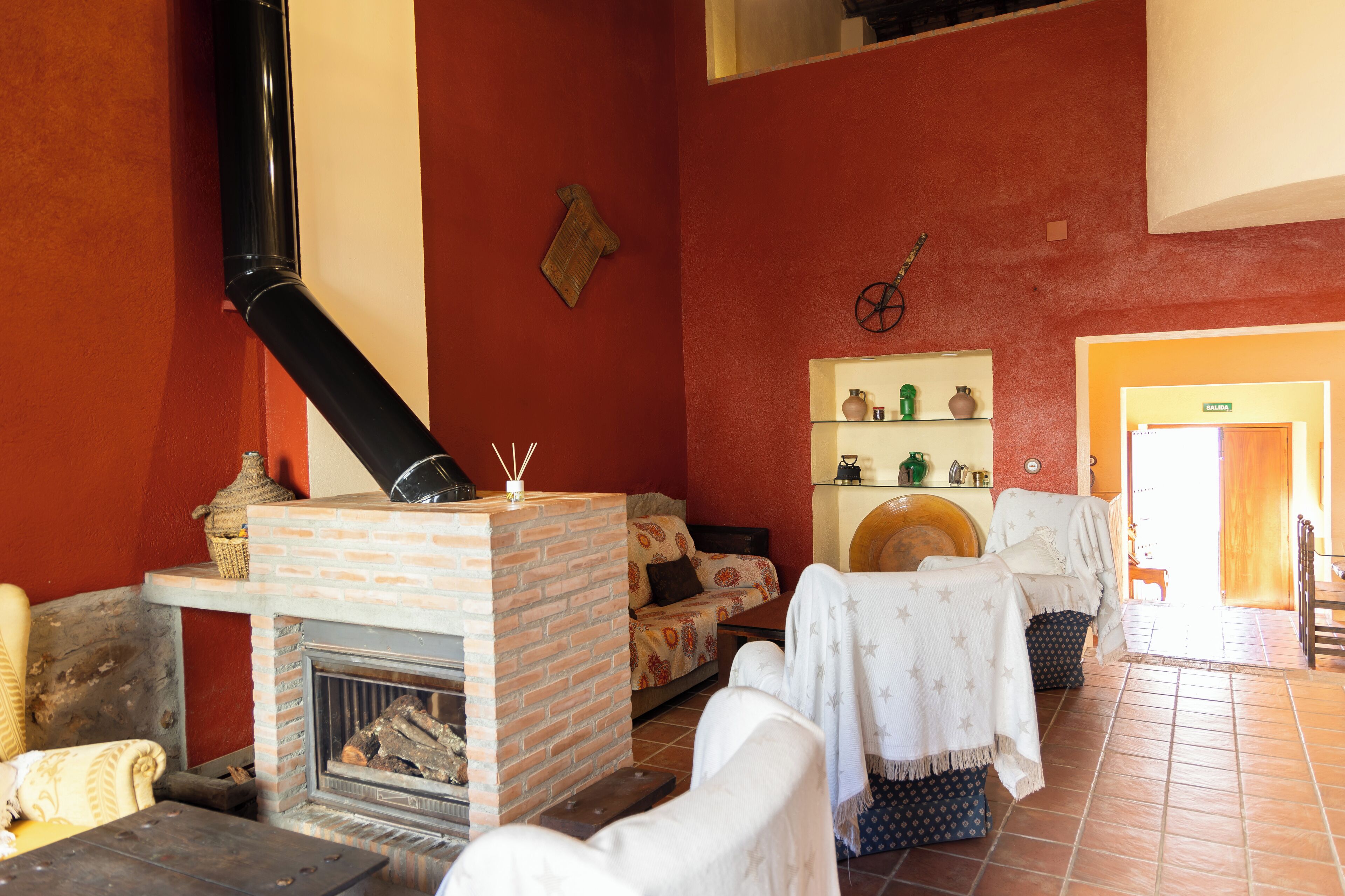 A cozy living room with a brick fireplace, a sofa, a dining table, and a shelf with decorative items.