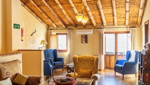 Un accogliente soggiorno con travi in legno, un divano, poltrone e un tavolino.