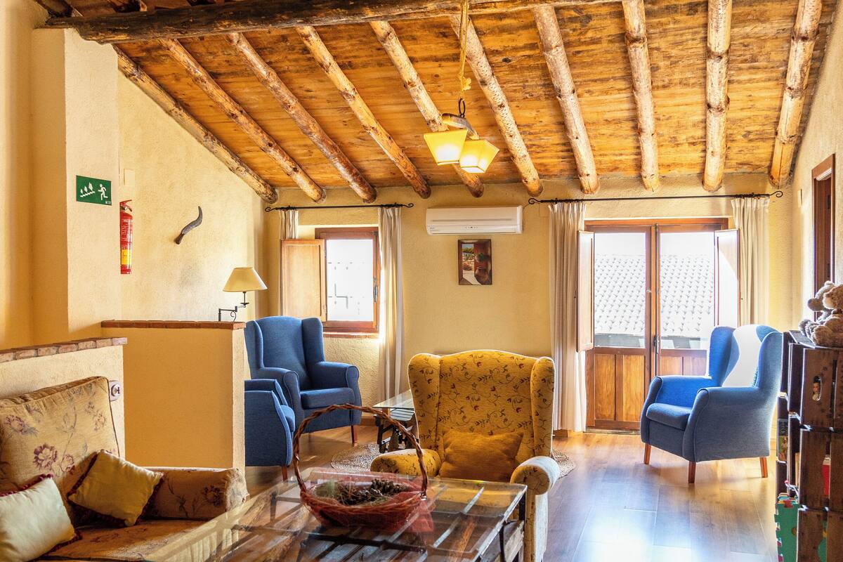 Un salón acogedor con vigas de madera, un sofá, sillones y una mesa de centro.