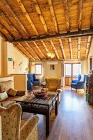 Un salón acogedor con vigas de madera, un sofá, sillones y una mesa de centro.