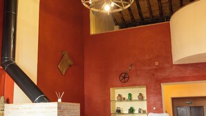 Una stanza con camino in mattoni, lampadario a sospensione e pavimento piastrellato.