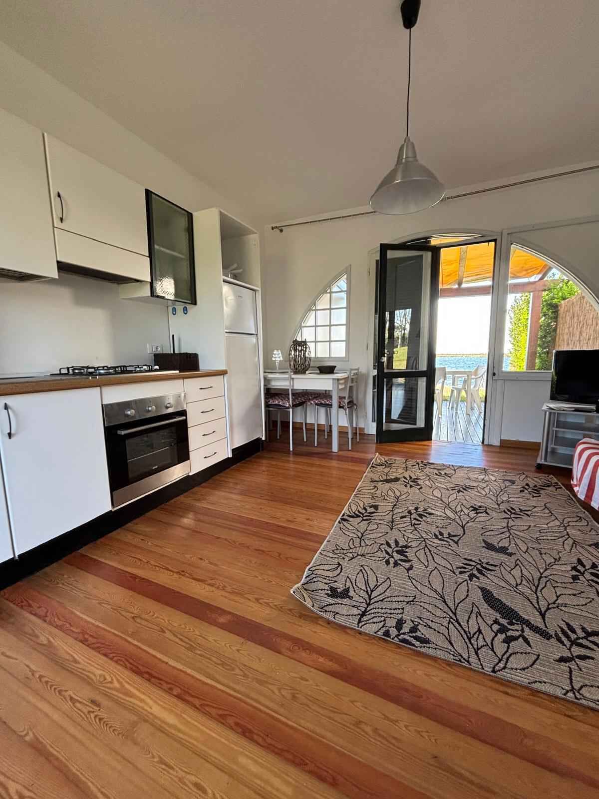 A modern kitchen with white cabinets, a built-in oven, and a dining area with a table and chairs.
