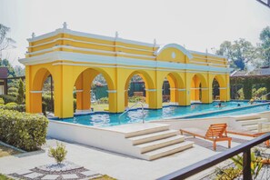 Un bâtiment jaune, doté d’arcades et d’une piscine.