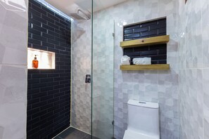 Une salle de bain moderne avec une douche à parois de verre, des toilettes et une étagère contenant des articles de toilette.