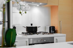 A modern kitchen with a gas stove, a toaster, and a pot on the counter.