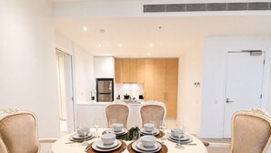 A dining area with a round table set for four, surrounded by upholstered chairs.