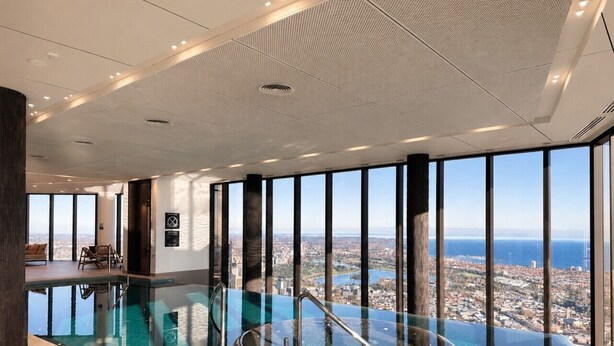 A modern indoor swimming pool with a glass barrier, large windows, and a city view.