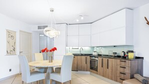 A modern kitchen with white cabinets, a wooden countertop, and a dining area with a round table and chairs.