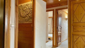A hallway with wooden walls and doors, leading to a bedroom with a bed and a shower. - Courchevel Moriond - Apartment 6 ppl, 3 bdr, Private Parking (Courchevel)