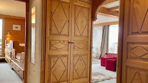 A wooden wardrobe with geometric patterns, a wooden bench with storage, and a red sofa in a room with wooden walls and ceiling. - Courchevel Moriond - Apartment 6 ppl, 3 bdr, Private Parking (Courchevel)
