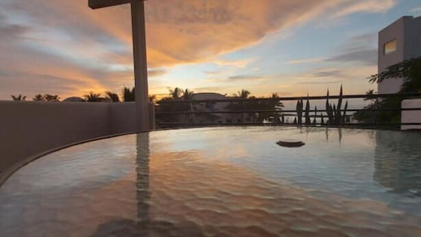 A glass-top table with a view of a sunset over a body of water, surrounded by a railing and palm trees. - Waterfront retreat in Casablanca (Same)