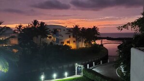 A coastal hotel with a curved road leading to the entrance, palm trees, and a sunset view. - Waterfront retreat in Casablanca (Same)