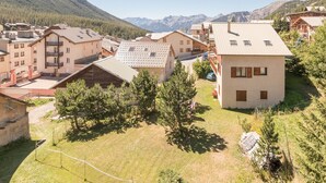 Un villaggio di montagna con edifici in stile chalet tradizionale, cielo sereno e vista sulle montagne lontane.