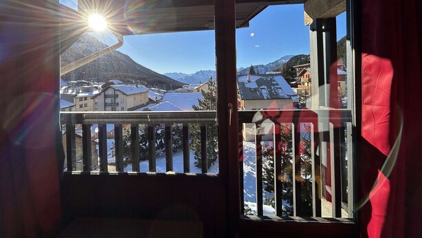 Un balcone con vista su un paesaggio montano innevato e un lago.