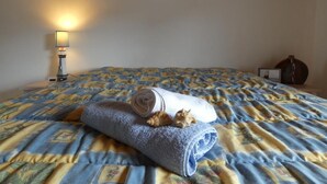 A neatly made bed with a patterned bedspread, a rolled towel, and a small decorative item on the bed. - House in Fromentine 65m², 4 pers, close to beach, parking (La Barre-de-Monts)
