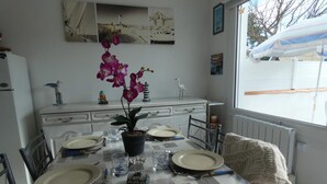 A dining table set for four with plates, cutlery, and a potted orchid. - House in Fromentine 65m², 4 pers, close to beach, parking (La Barre-de-Monts)