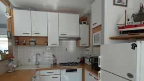 A compact kitchen with white cabinets, a stove, a sink, and a microwave. - House in Fromentine 65m², 4 pers, close to beach, parking (La Barre-de-Monts)