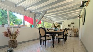 Un comedor con una mesa y sillas de madera, un jarrón con flores y un farol sobre una mesita.