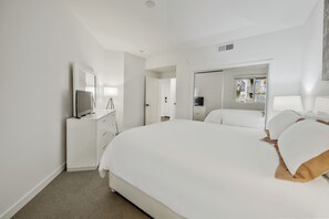 Una habitación de hotel moderna con una cama grande, un televisor, un escritorio con lámpara y un armario.