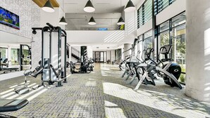 A modern gym with exercise equipment, large windows, and a brick floor.