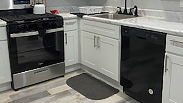 A modern kitchen with white cabinets, a black microwave, stainless steel oven, and dishwasher.