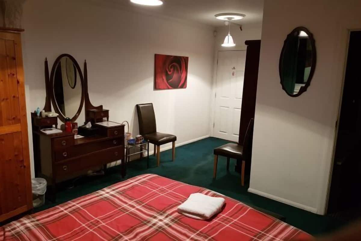 A bedroom with a bed, dresser, mirror, and a painting on the wall.