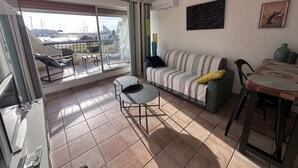 A living room with a balcony, a sofa, a table, and a chair.
