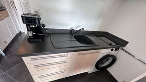 A compact kitchen with a coffee maker, sink, and washing machine. - Air-conditioned Studio-Cabin for 4 pers. with private parking, near beach in Port Camargue (Le Grau-du-Roi)