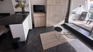 A modern kitchen with a flat-screen TV, wooden cabinets, a black countertop, and a small rug. - Air-conditioned Studio-Cabin for 4 pers. with private parking, near beach in Port Camargue (Le Grau-du-Roi)