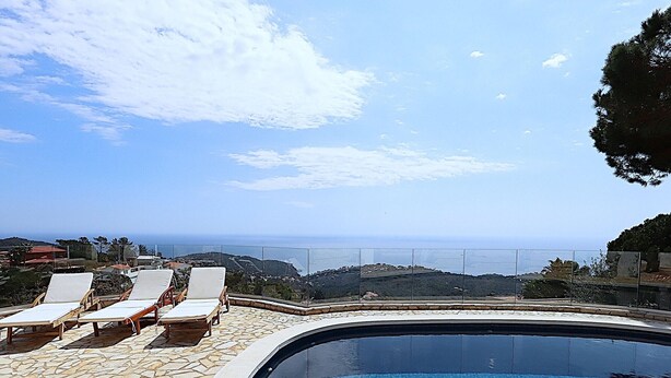 Una piscina con sillas de descanso y una vista panorámica del océano.