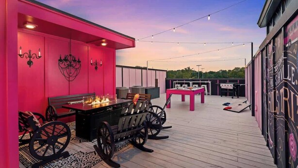 An outdoor patio area with a dining table and chairs, string lights, and a fire feature.