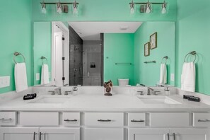 A bathroom with two sinks, a large mirror, and a shower area.