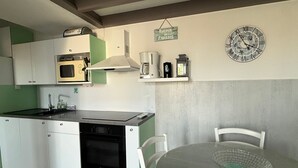 A kitchen with white cabinets, a Bosch oven, a microwave, a coffee maker, and a clock on the wall.